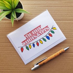 Stranger Things Christmas card, front reads Merry Christmas in Stranger things font with Stranger things lights